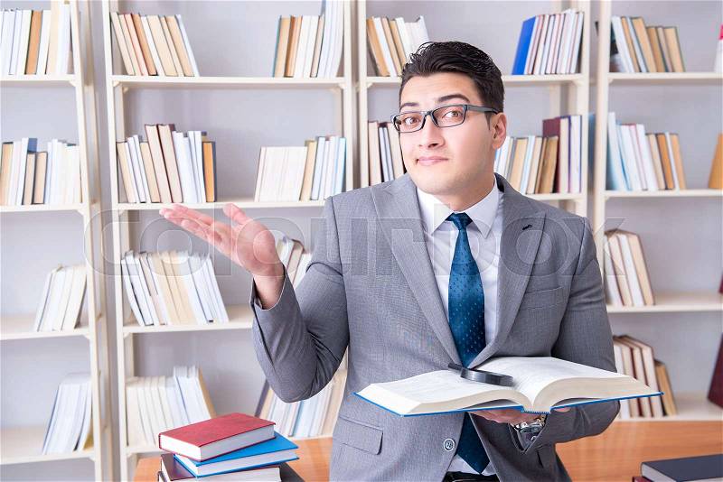 Business law student with magnifying glass reading a book, stock photo