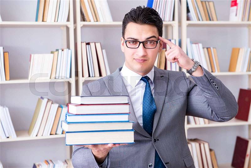 Business law student with pile of books working in library, stock photo