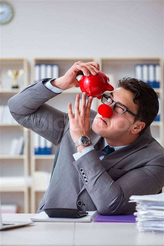 Clown businessman with piggy bank doing accounting, stock photo