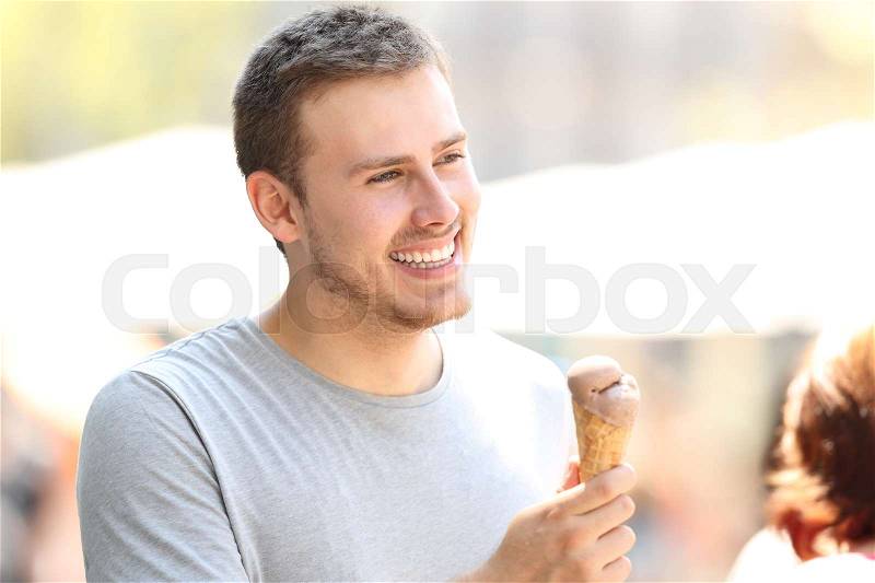 Happy man walking and holding a chocolate ice cream in the street, stock photo