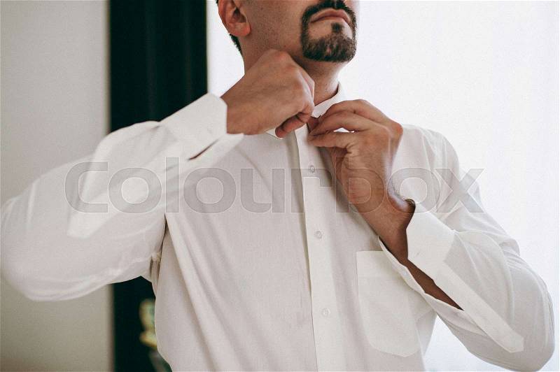 Man buttoning his shirt, stock photo