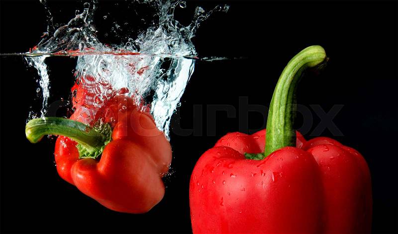 Splash water from water droping bell pepper mixed with focus another bell pepper in black background with studio lighting. in black background with studio lighting, stock photo