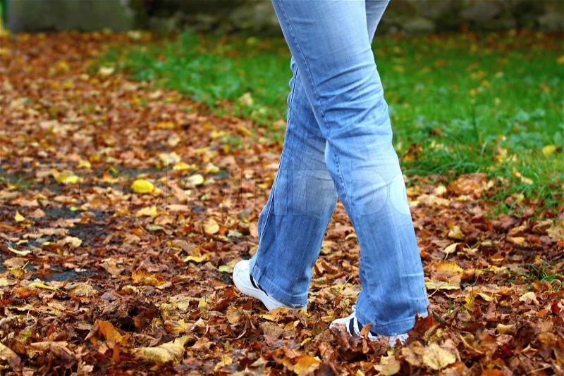 Walking through park, Woman\'s legs walking through the leaves of fall, stock photo