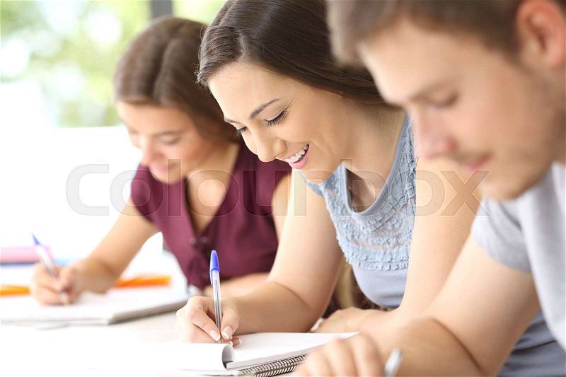 Happy student taking notes during a class in a classroom, stock photo