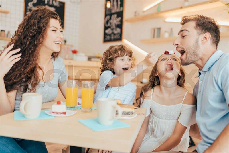 Beautiful young family eating sweets in cafe with modern trendy interior, stock photo