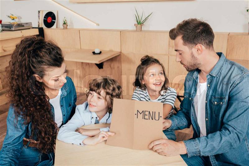 Beautiful young family with menu list in cafe, stock photo