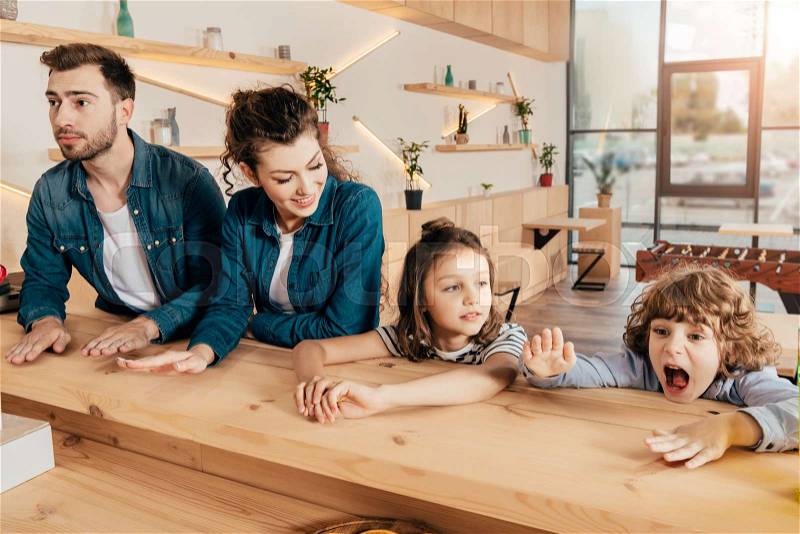 Beautiful young family in restaurant at bar counter, stock photo