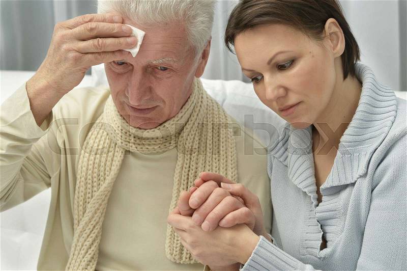 Young woman taking care of ill senior man, stock photo