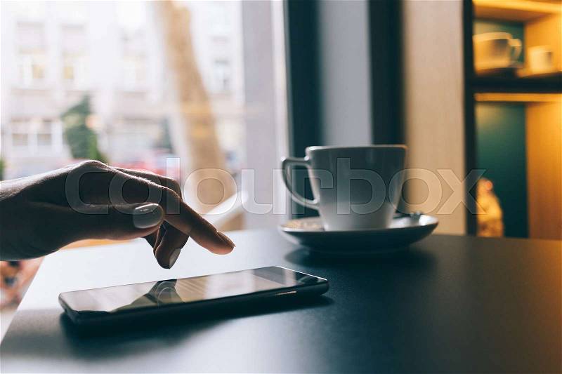 Female hand uses a mobile phone with a touch screen close-up, stock photo