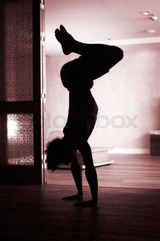 Male yoga teacher doing handstand inversion alisthenics and yoga asana practice in gym fitness pilates studio, stock photo