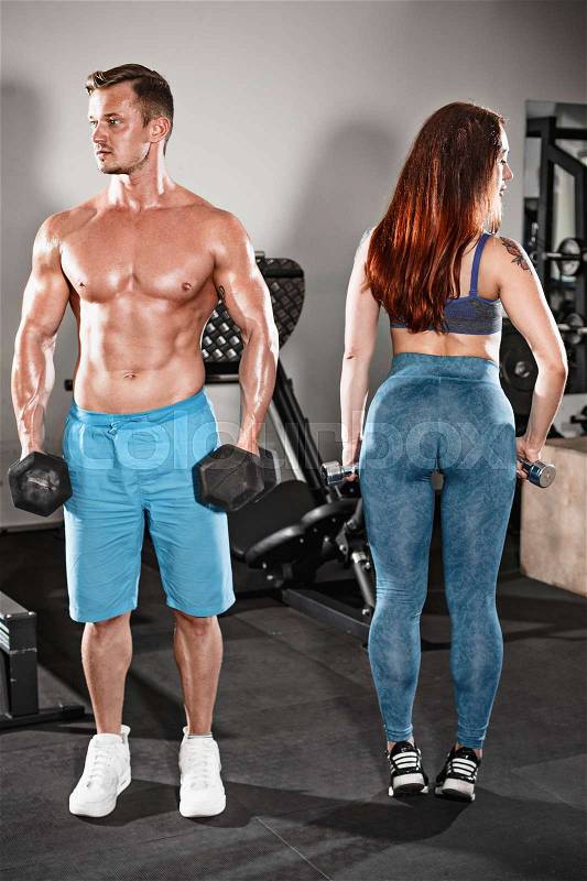 The sport fit couple posing at gym. Work in pairs with dumbbells, stock photo