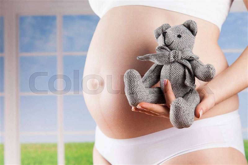 Teddy bear and Happy pregnant woman, stock photo