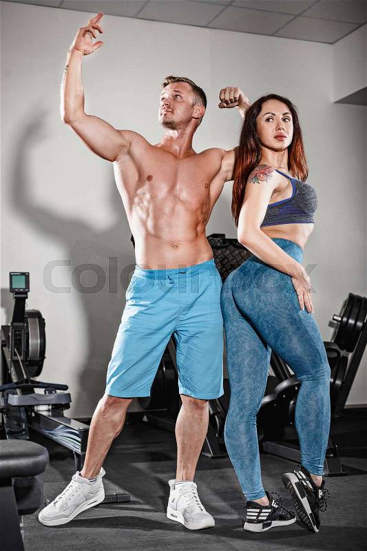 The sport fit couple posing at gym. Work in pairs with dumbbells, stock photo