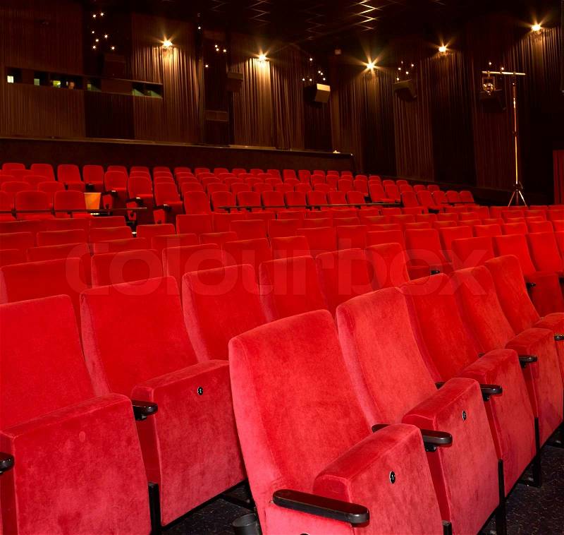 Indoor scenery showing a movie theater with red seats in warm ambiance, stock photo