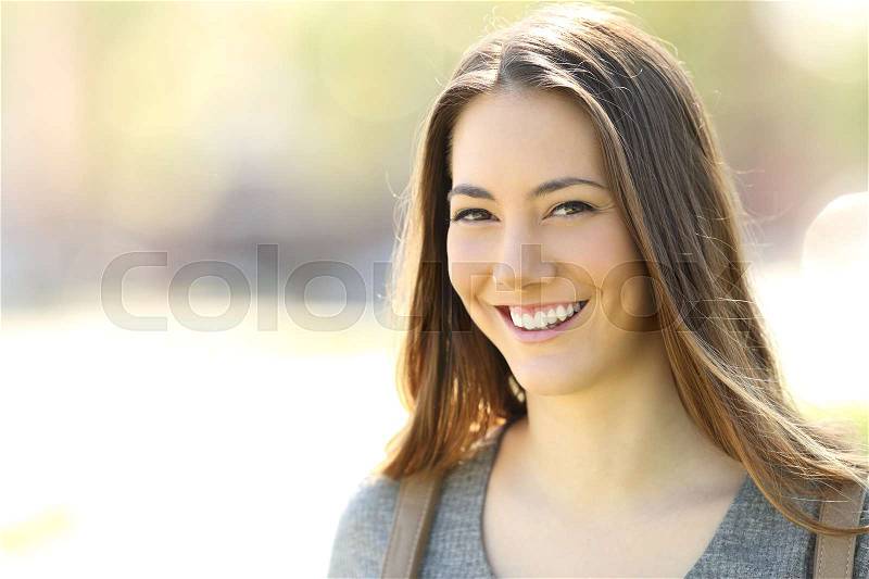 Happy woman with perfect smile looking at camera outdoors in the street, stock photo