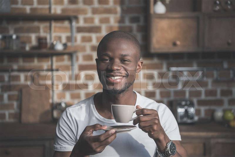 Handsome african american man having his morning coffee at home, stock photo