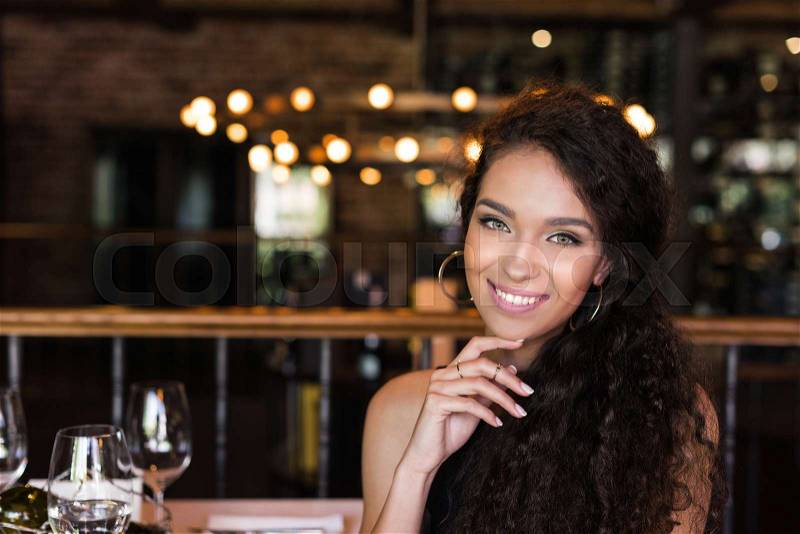 Portrait of young beautiful woman sitting in restaurant, smiling and looking at camera , stock photo