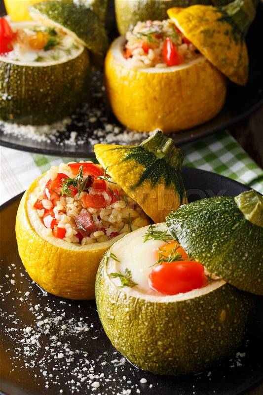Green zucchini baked with eggs and yellow zucchini stuffed with bulgur close-up on a plate. vertical , stock photo