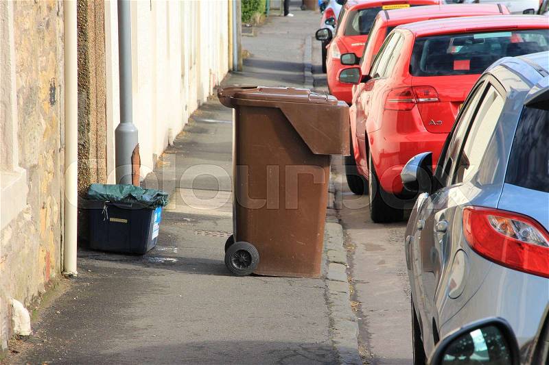Parking place for cars and the brown garbage can for recycling along the road in the city Stirling in Scotland in the summer, stock photo