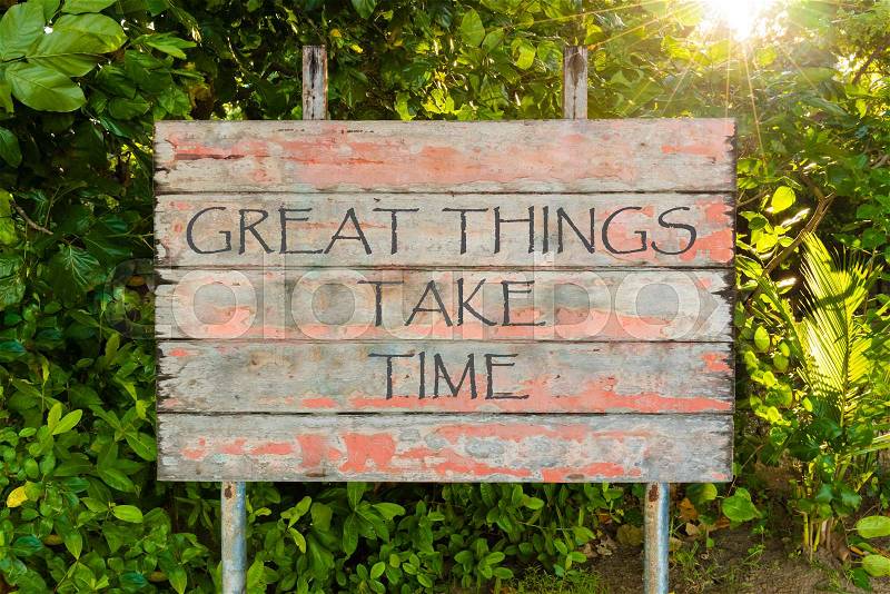 Great Things Take Time motivational quote written on old vintage board sign in the forrest, with sun rays in background, stock photo