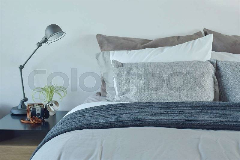Blue and gray color scheme bedding with industrial style table lamp, stock photo