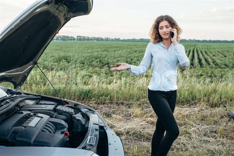 Young woman calls to emergency service, broken car. Trouble with vehicle on road in summer day, stock photo