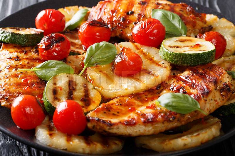 Chicken fillet grilled with pineapple, zucchini and tomato close-up on a plate. horizontal , stock photo