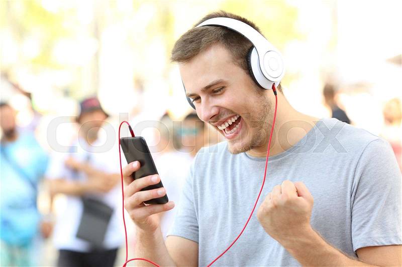 Excited guy receiving good news on a mobile phone on the street, stock photo
