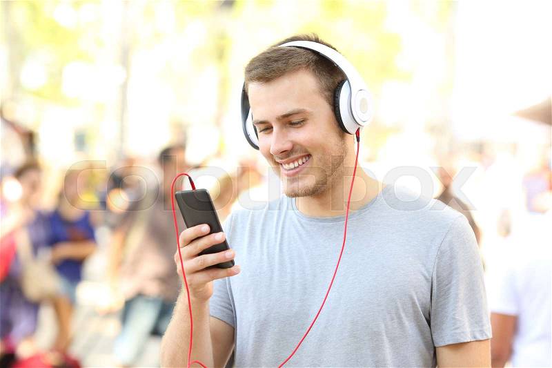 Guy watching and listening media content on phone on the street, stock photo