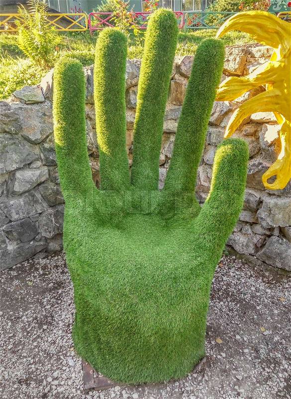 Green hand made from grass in the public park, stock photo