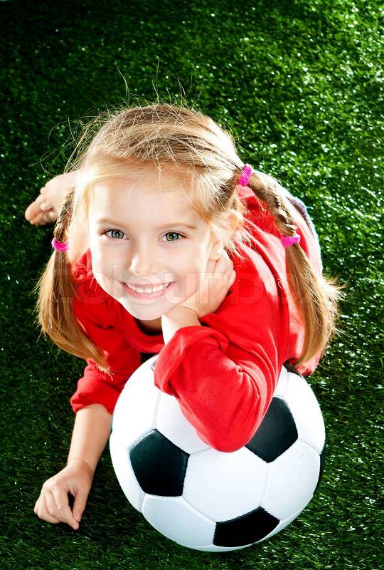 Little girl with soccer ball in boots on a green lawn, stock photo