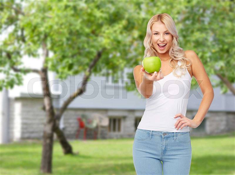 Healthy eating, diet and people concept - happy beautiful young woman with green apple over summer garden background, stock photo
