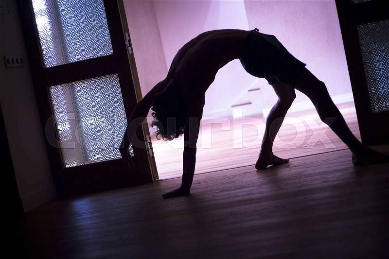 Male yoga teacher doing handstand calisthenics and yoga asana practice in gym fitness pilates studio, stock photo
