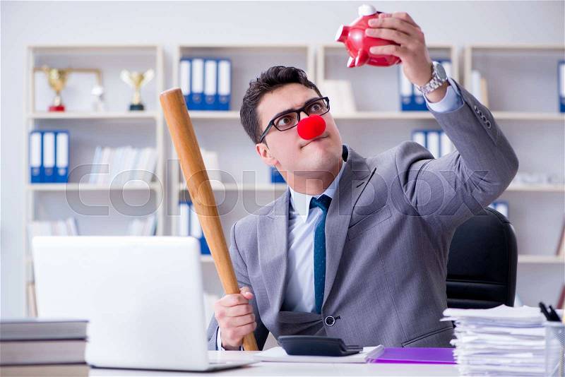 Clown businessman with a baseball bat and a piggy bank, stock photo