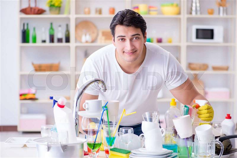 Man enjoying dish washing chores at home, stock photo