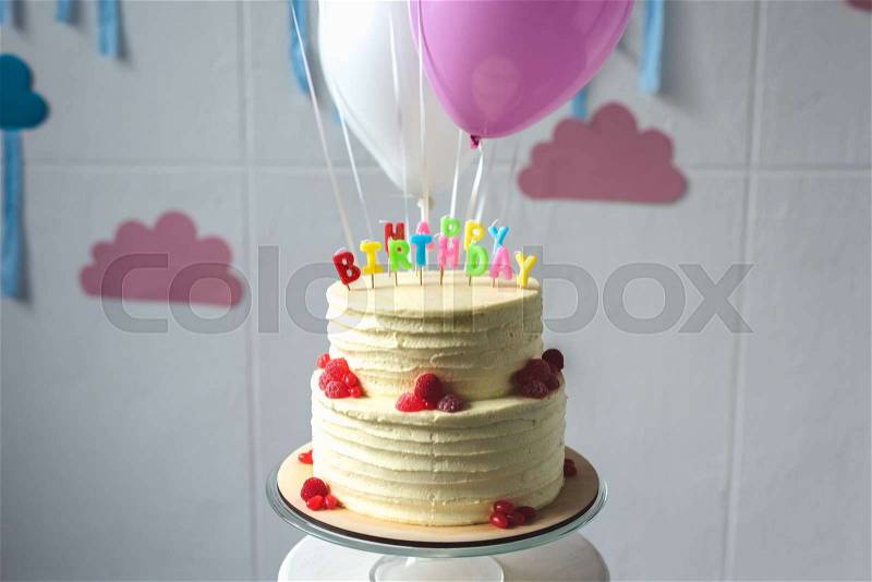 Delicious birthday cake with balloons arranged in decorated room, stock photo