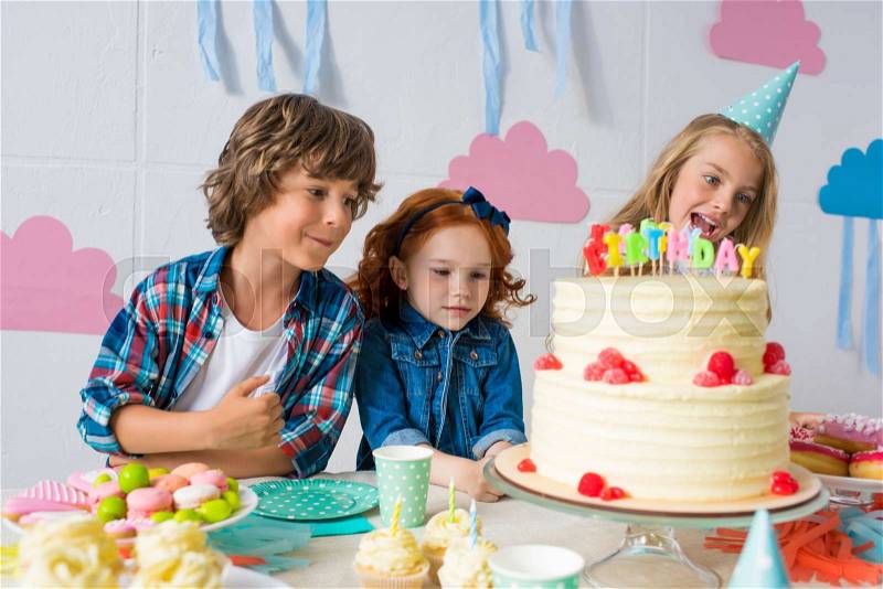 Adorable happy kids eating delicious sweets at birthday table , stock photo