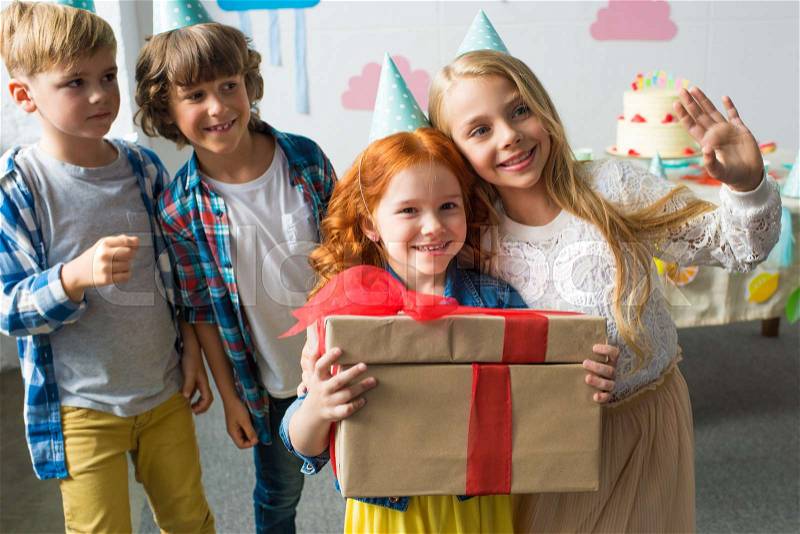 Adorable happy kids holding gifts while standing together at birthday party, stock photo
