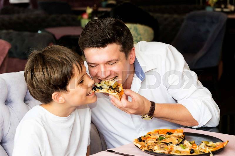 Father son eating an Italian pizza at a pizzeria, stock photo