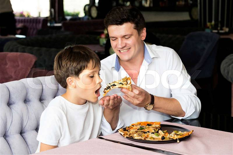 Father son eating an Italian pizza at a pizzeria, stock photo