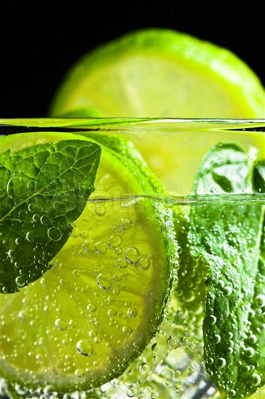 cocktail with lime , ice and peppermint on black background, stock photo