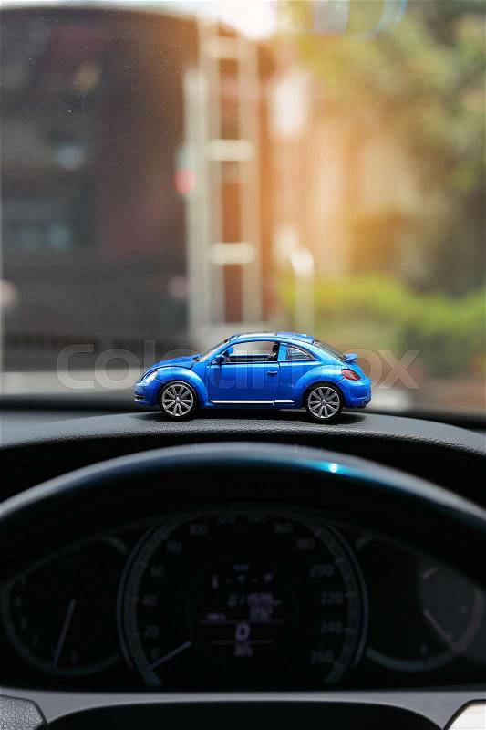 Blue toy small vehicle on car console with traffic jam in city background, stock photo