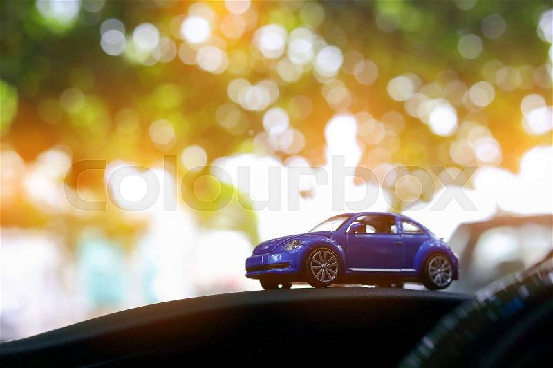 Small blue vehicle car toy driving travel road trip image concept in bokeh green nature with beautiful sun light shiny background, stock photo