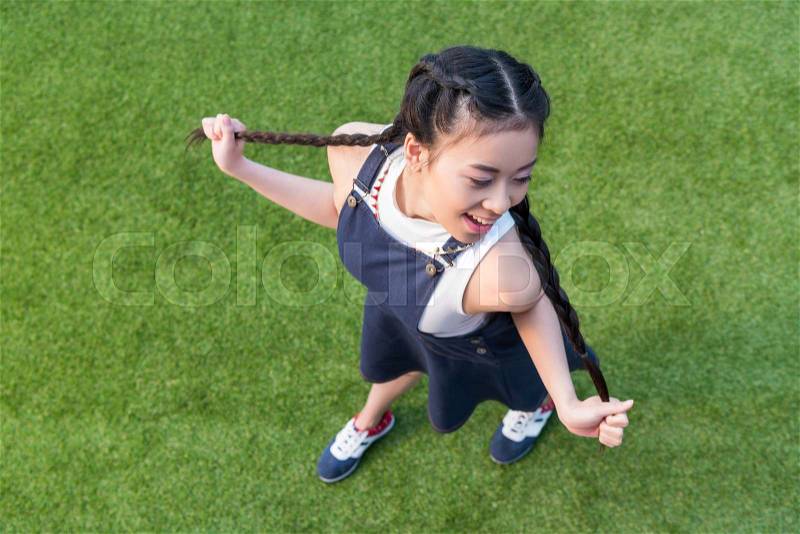 High angle view of beautiful smiling asian girl posing while standing on green grass, stock photo