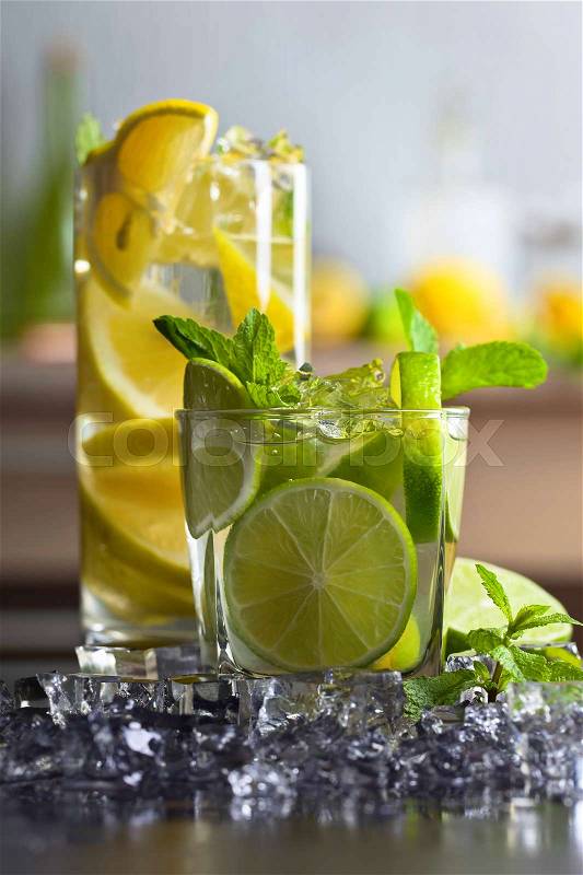 Cocktails with lime , lemon , ice and peppermint leaves on a black table , stock photo