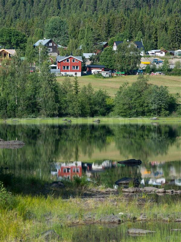 Typical red and white houses in norway with reflection in the water of the leira fjord in middle norway, stock photo