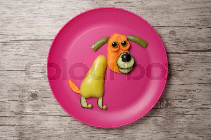 Dog made of vegetables on plate and desk, stock photo