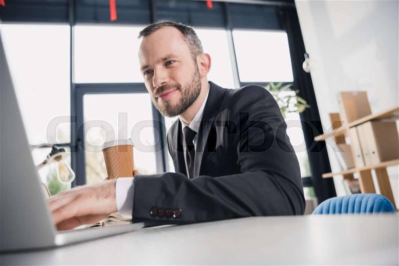 Happy young businessman working with laptop, stock photo
