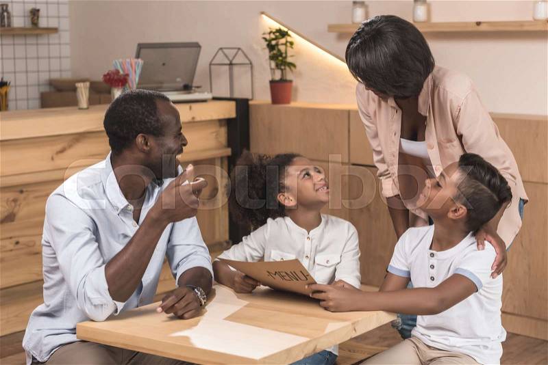 Excited african-american family looking at menu list in cafe, stock photo