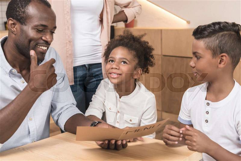 Happy african-american family looking at menu list in cafe, stock photo